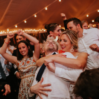 Bride and groom dancing joyfully under warm string lights at Toad Hill Farm wedding reception.