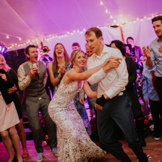 Bride and groom dancing under glowing lights at lively Toad Hill Farm wedding celebration.