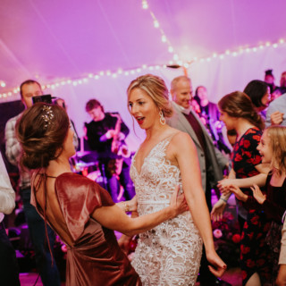 Bride and guests dancing joyfully under string lights at Toad Hill Farm wedding reception.