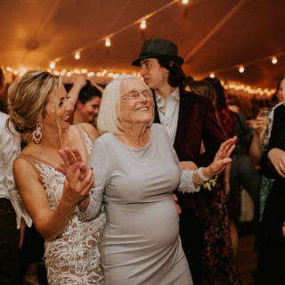 Grandmother and bride dancing joyfully under string lights at Toad Hill Farm wedding.