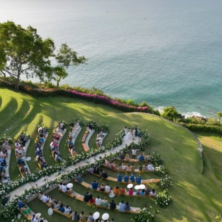 Romantic cliffside wedding in Bali with ocean views, floral arch, and elegant curved seating.