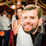Bride dancing with large face cutout at joyful Cunningham Farm wedding in New Gloucester, Maine.