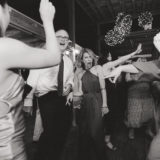 Guests laughing and dancing under string lights at a rustic Shady Lane Farm wedding celebration.