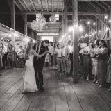 Bride and groom share first dance under string lights in rustic barn wedding celebration.