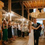 Bride dancing with her father under warm string lights at rustic barn wedding in Maine.
