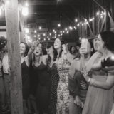 Guests singing and celebrating at a joyful rustic barn wedding in New Gloucester, Maine.
