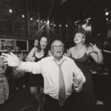 Older man dancing joyfully with guests at rustic barn wedding in New Gloucester, Maine.