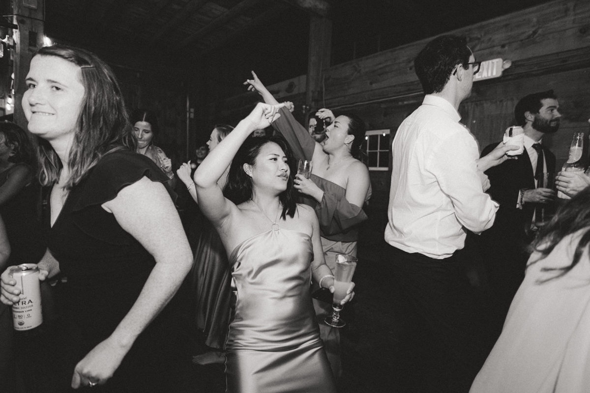 Guests dancing and celebrating at a rustic barn wedding reception in black and white.