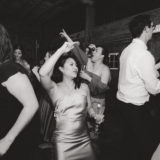 Guests dancing and celebrating at a rustic barn wedding reception in black and white.