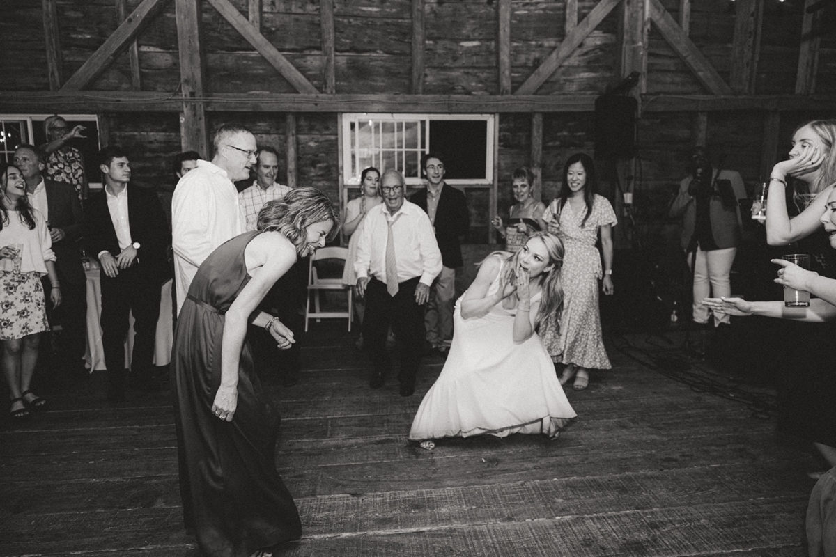 Bride and friend dancing joyfully in rustic barn wedding at Shady Lane Farm, New Gloucester Maine.
