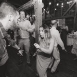 Guests dancing and laughing under string lights at a rustic barn wedding in Maine.