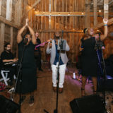 Live band performing soulful music in a warmly lit rustic barn wedding in New Gloucester, Maine.