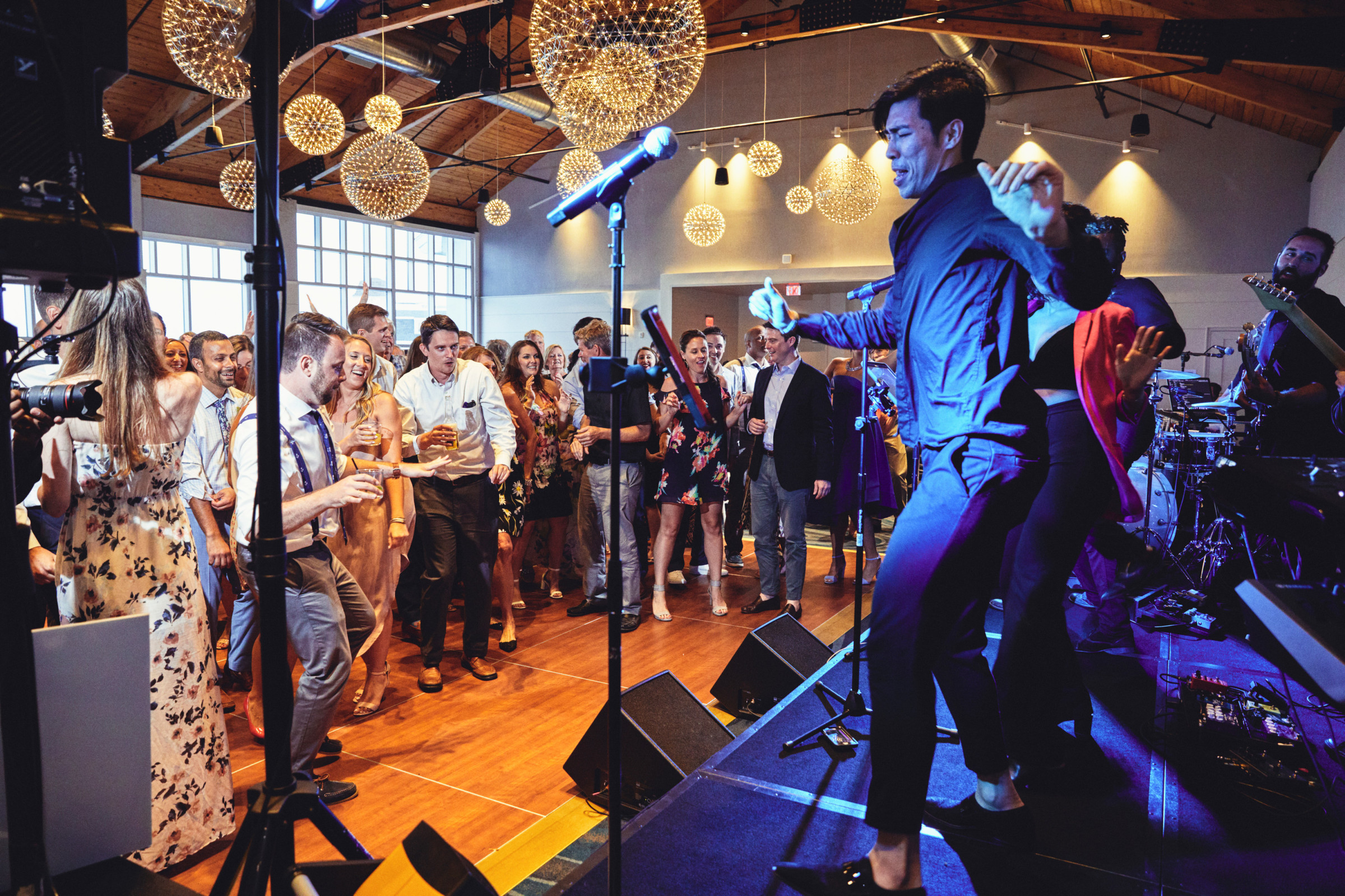 Guests dancing at a lively Cliff House wedding reception with live band and golden lighting.