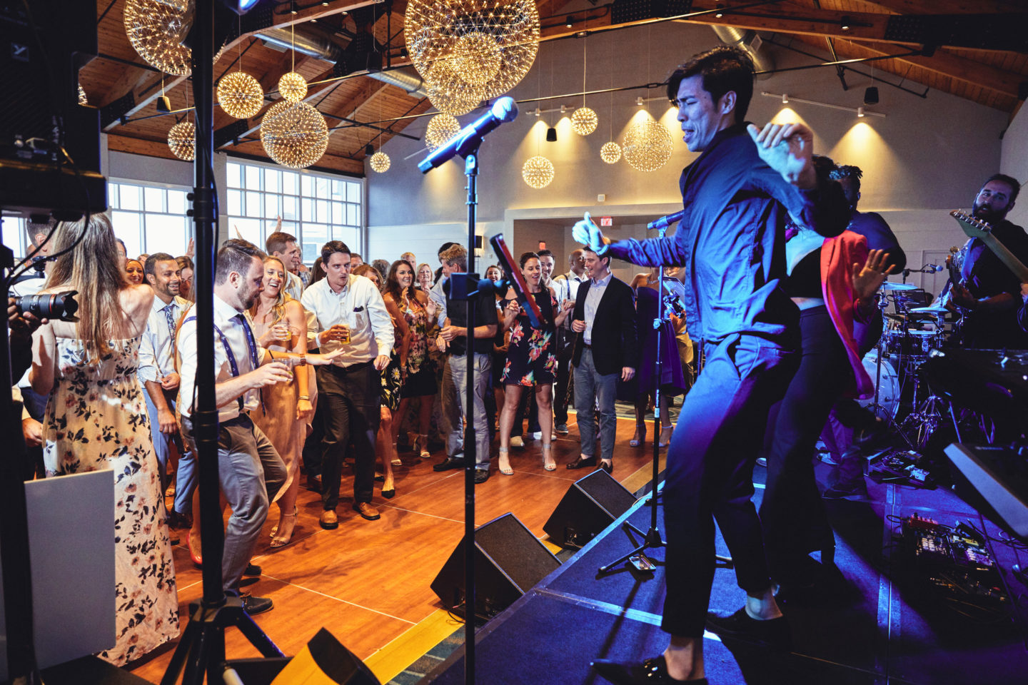 Energetic live band performing indoors with passionate singers and guitarist under vibrant stage lighting.