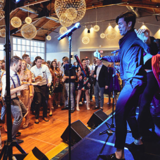 Guests dancing at a lively Cliff House wedding reception with live band and golden lighting.