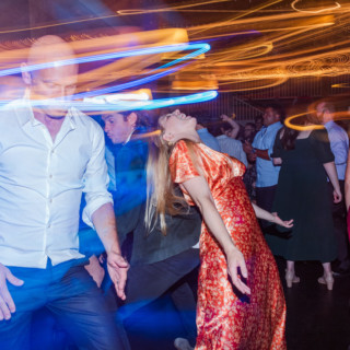 Guests dancing under colorful lights at a lively Gibbet Hill wedding in Groton, Massachusetts.