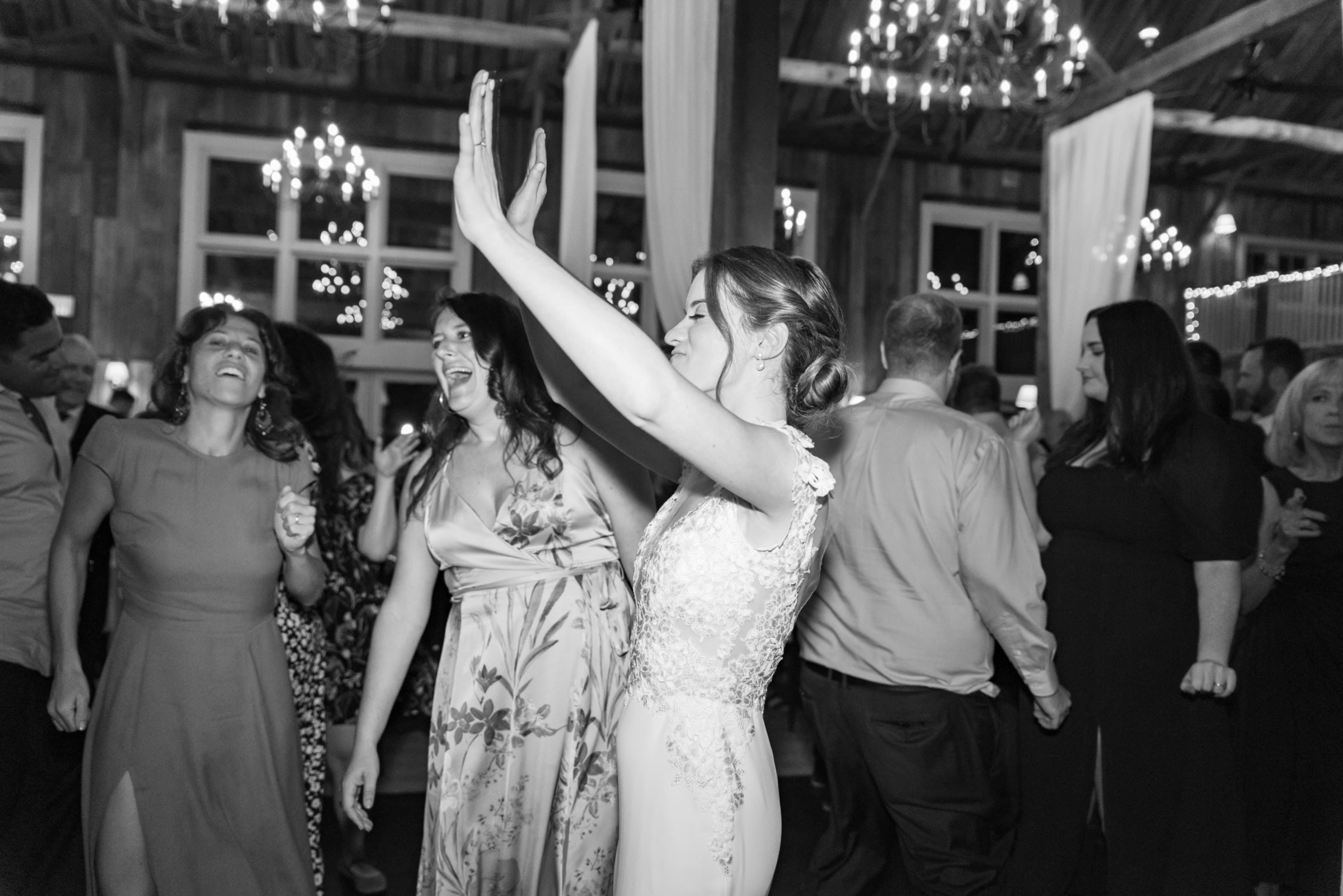 Bride dancing with friends at a rustic black-and-white wedding reception in Groton, Massachusetts.