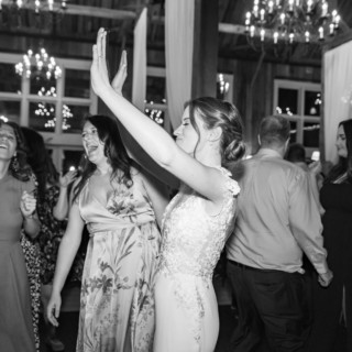 Bride dancing with friends at a rustic black-and-white wedding reception in Groton, Massachusetts.
