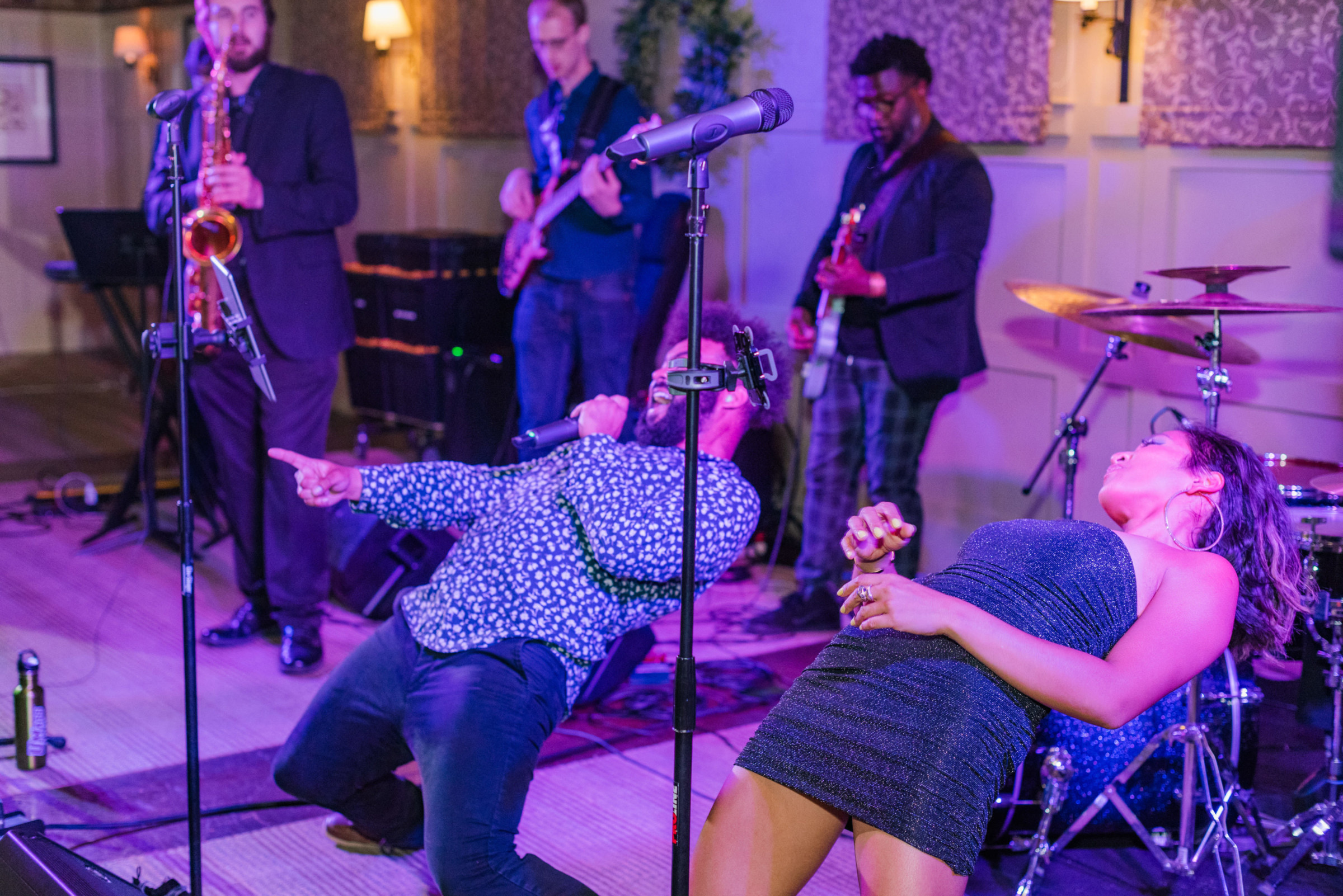 Energetic live band performance with passionate singers and musicians in a colorful indoor venue.