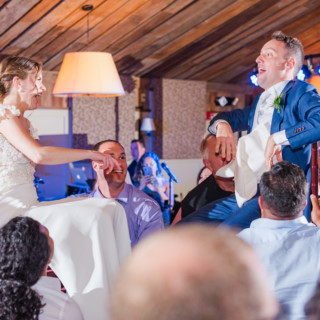 Bride and groom lifted on chairs during joyful Hora dance at Gibbet Hill wedding celebration.