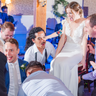 Bride and groom lifted on chairs during joyful Hora dance at Gibbet Hill wedding.