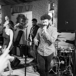 Black and white photo of lively wedding band performing at intimate indoor venue in Groton Massachusetts.