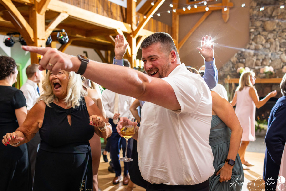 Guests laughing and cheering during a joyful Harrington Farm wedding reception in Princeton, Massachusetts.