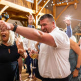 Guests laughing and cheering during a joyful Harrington Farm wedding reception in Princeton, Massachusetts.