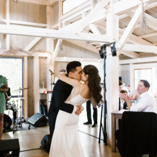 Newlyweds share a romantic first kiss at a rustic barn wedding in Wiscasset, Maine.