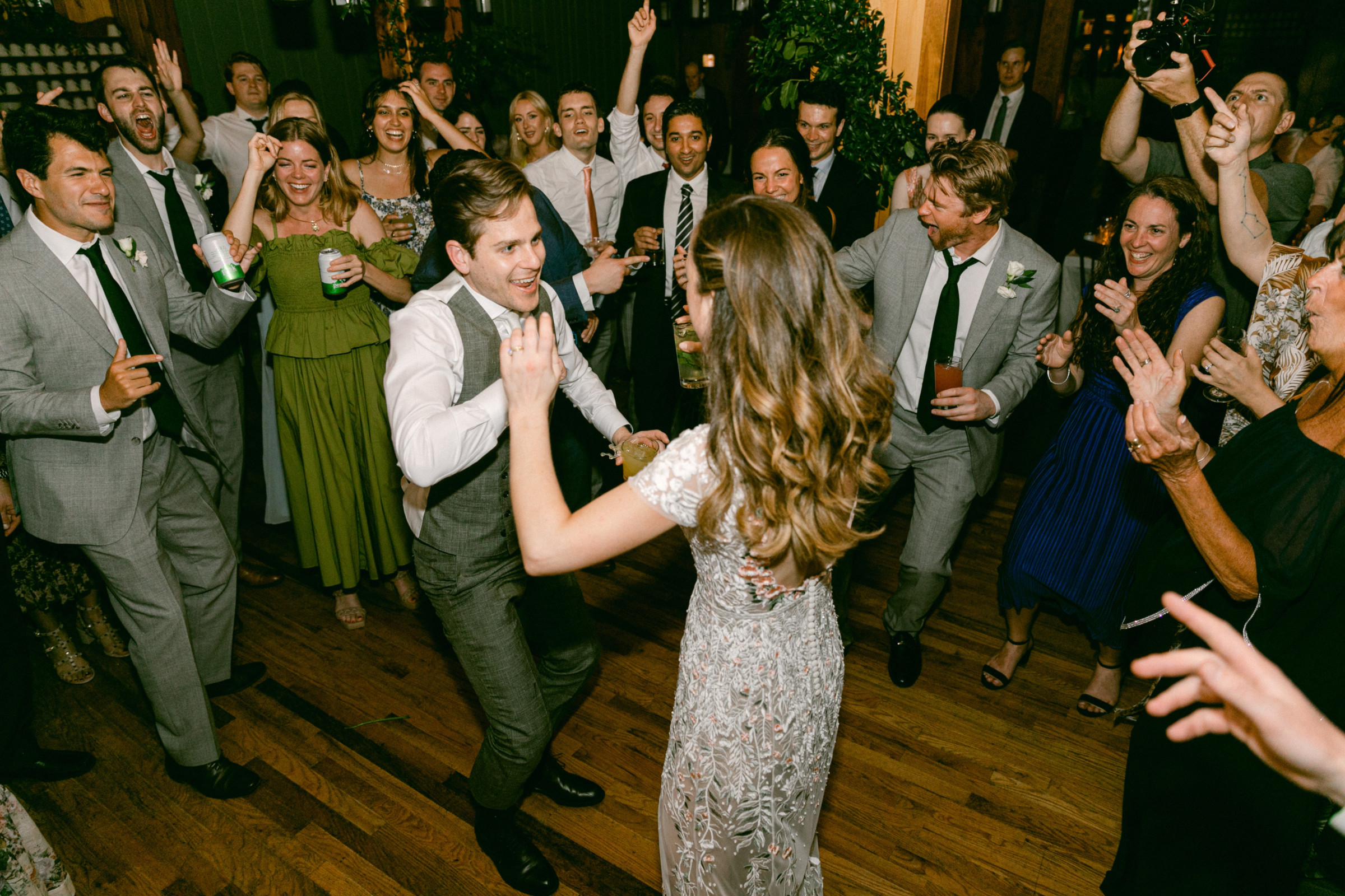 Bride and groom dancing joyfully at Migis Lodge wedding surrounded by cheering guests in Maine.