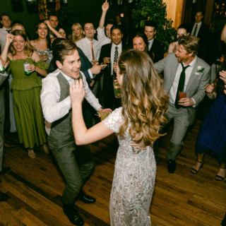 Bride and groom dancing joyfully at Migis Lodge wedding surrounded by cheering guests in Maine.