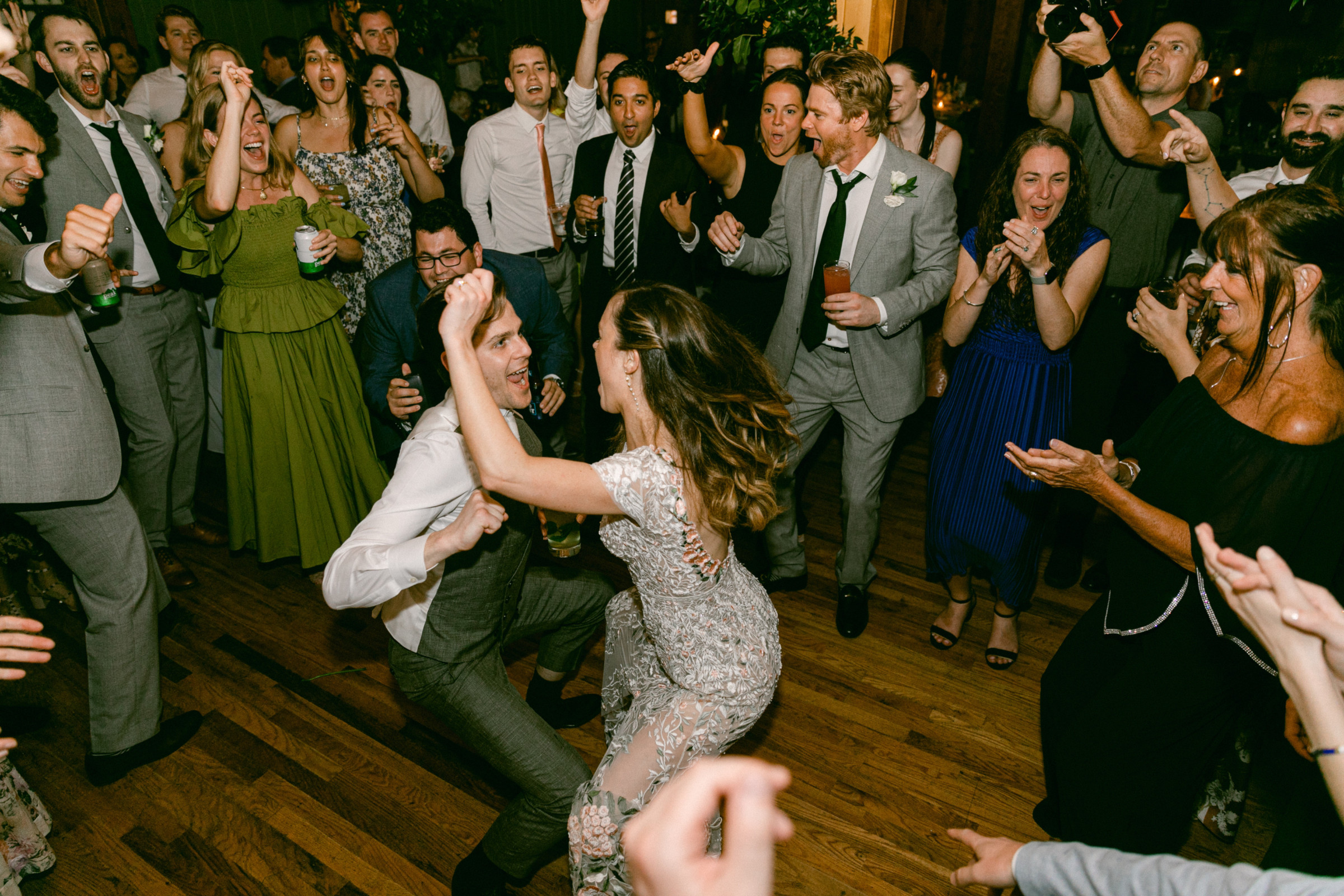 Bride and groom dancing joyfully surrounded by cheering guests at Migis Lodge wedding in Maine.