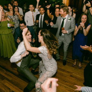 Bride and groom dancing joyfully surrounded by cheering guests at Migis Lodge wedding in Maine.