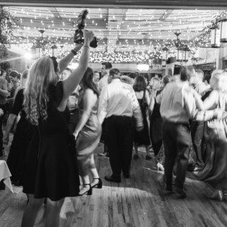 Guests celebrating a joyful wedding under glowing string lights at Migis Lodge in Maine.