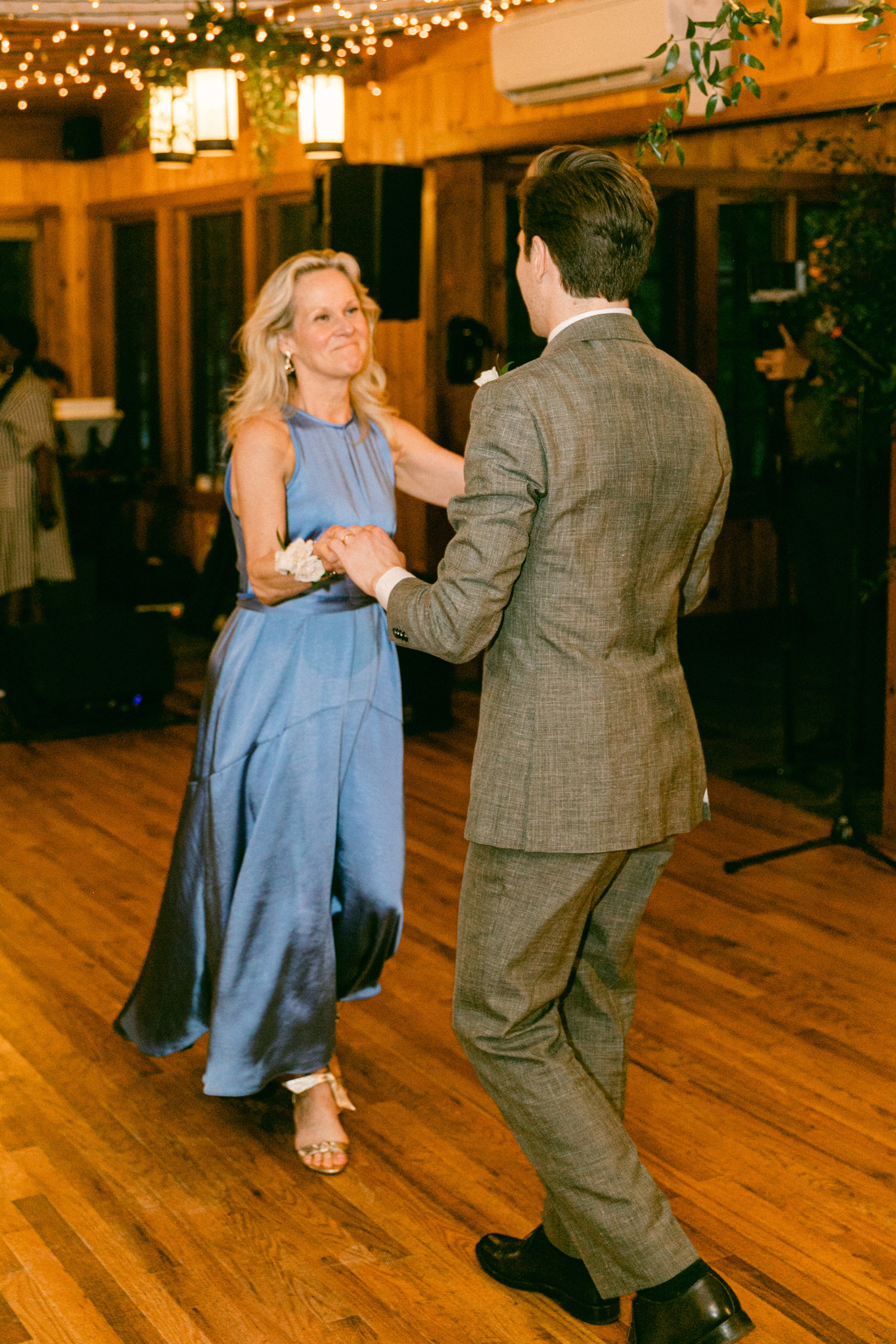 Mother and son share a joyful dance at a rustic Migis Lodge wedding in Maine.