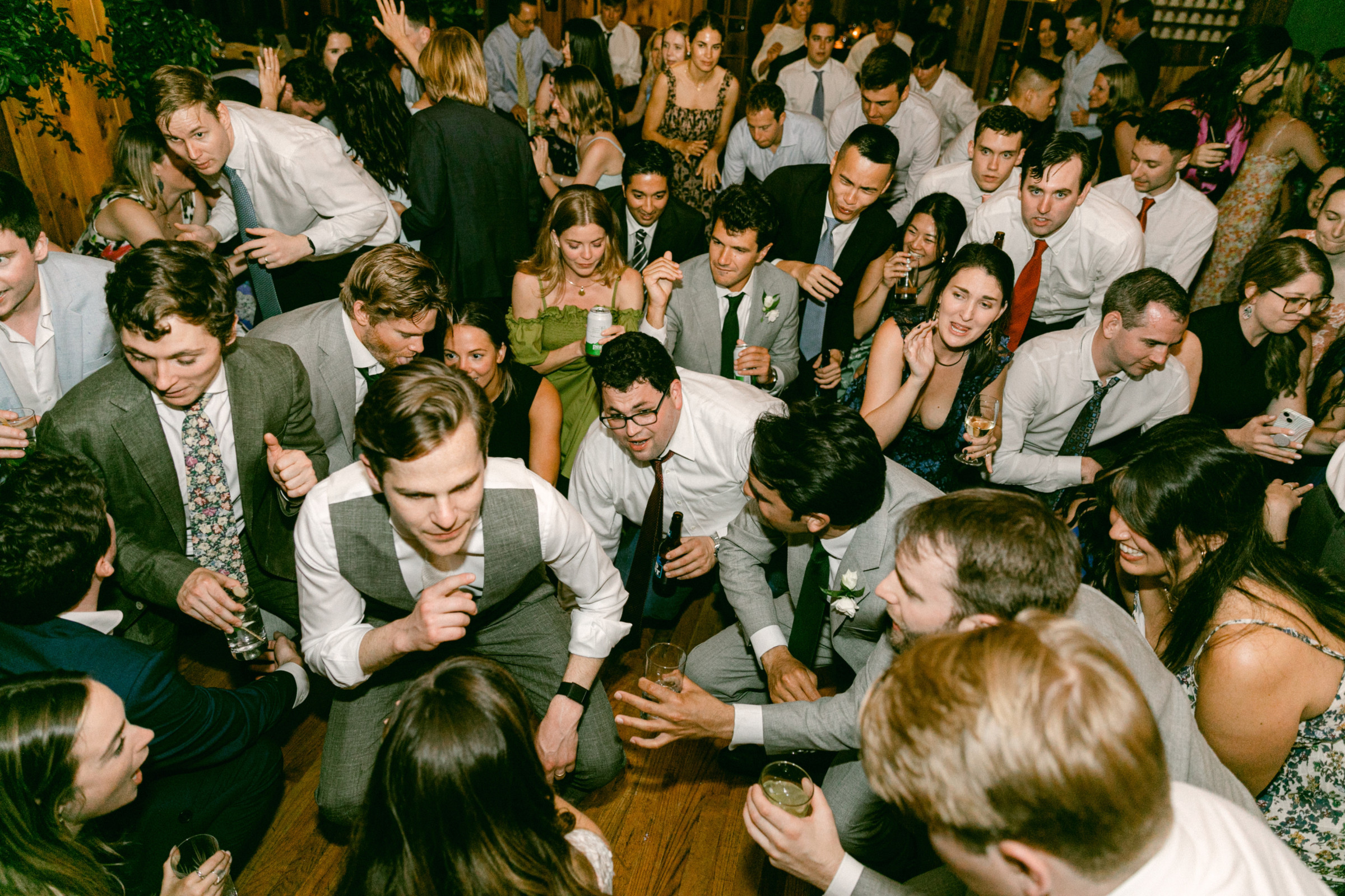Wedding guests dancing and cheering at a lively Migis Lodge reception in South Casco, Maine.
