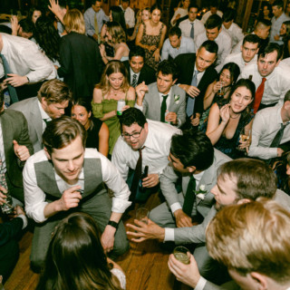 Wedding guests dancing and cheering at a lively Migis Lodge reception in South Casco, Maine.