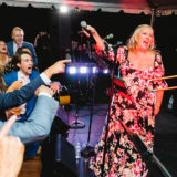 Bride sings as guests cheer during lively Marblehead wedding celebration.