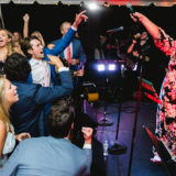 Bride leads joyful wedding sing-along under glowing tent lights in Marblehead, Massachusetts.
