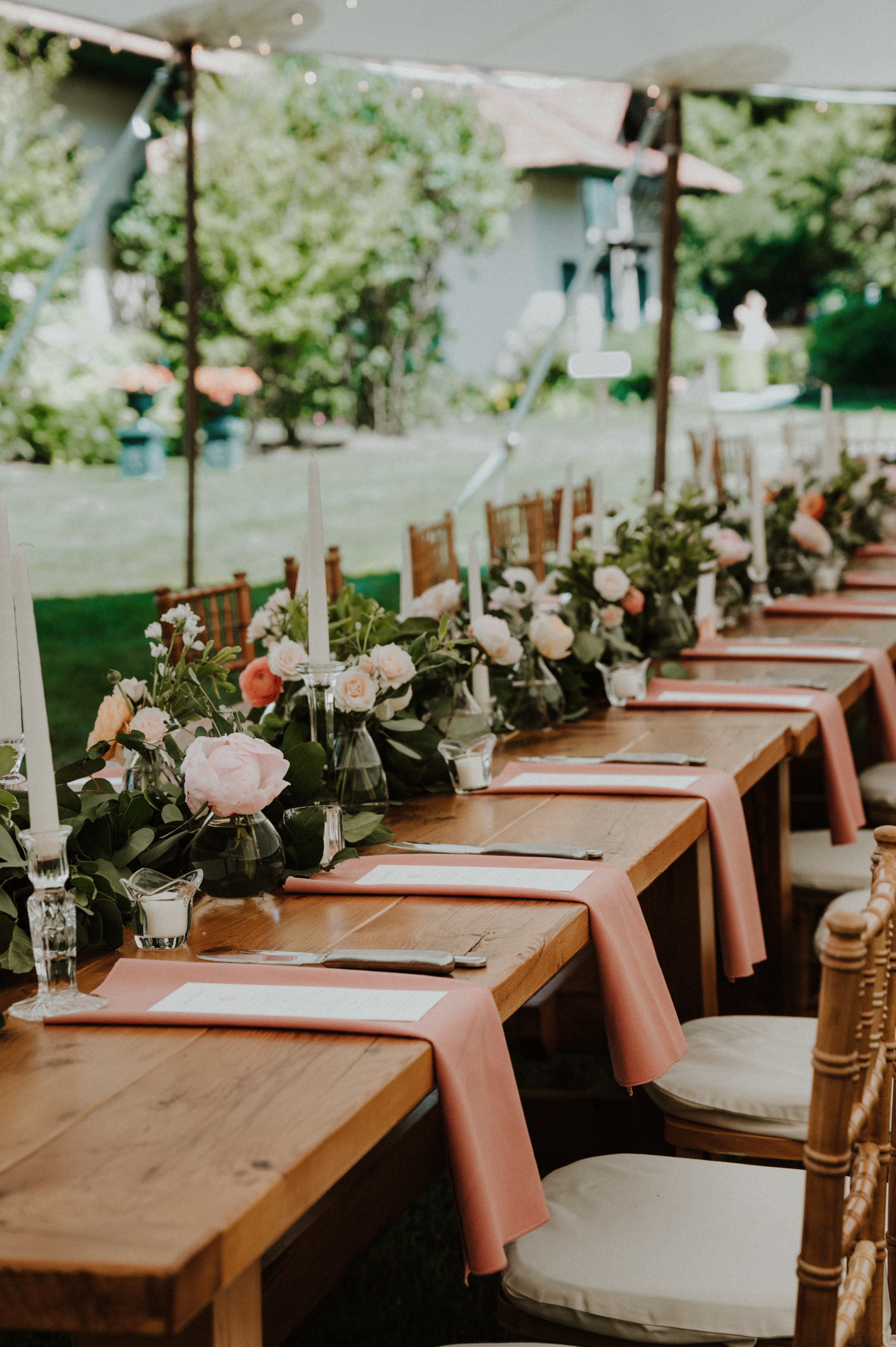 Elegant outdoor wedding table with pink napkins, candles, and floral centerpieces at River Road Farm.