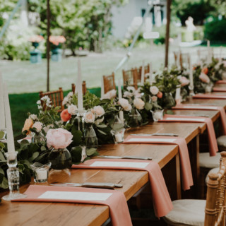 Elegant outdoor wedding table with pink napkins, candles, and floral centerpieces at River Road Farm.