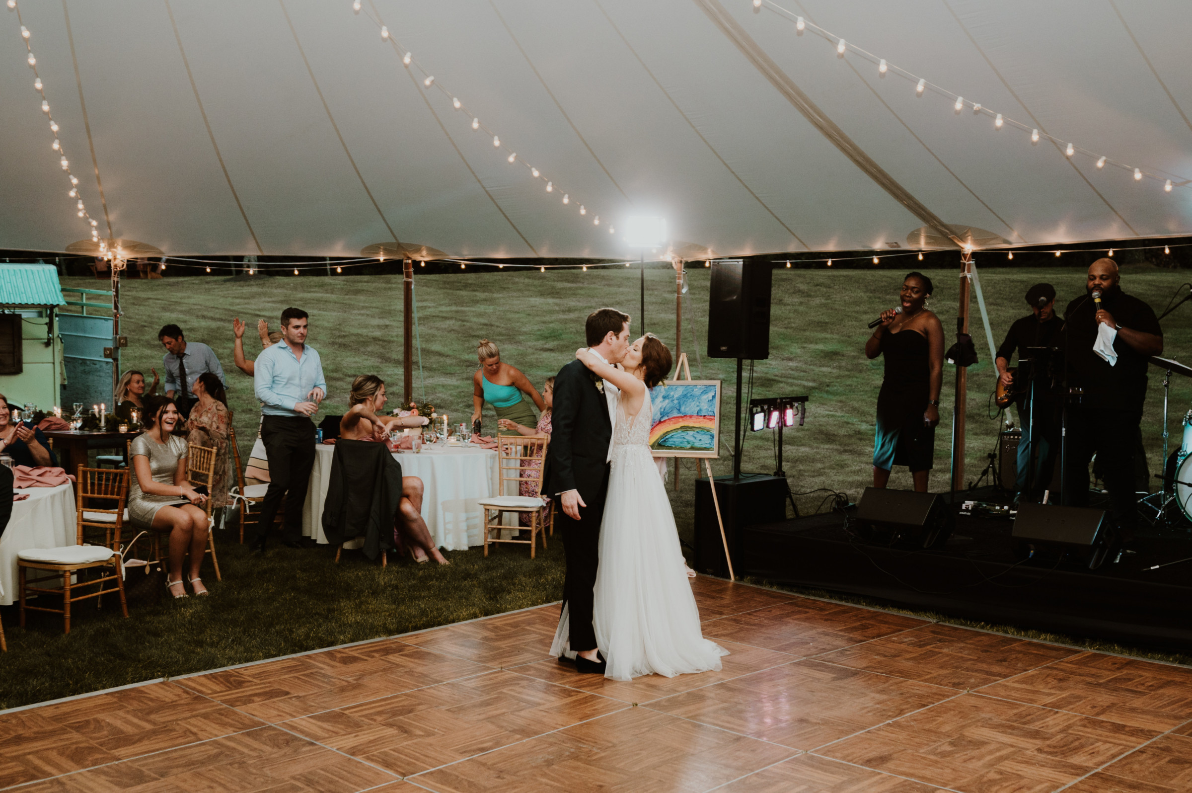 Bride and groom share a romantic first dance under glowing string lights at Vermont wedding.