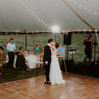 Bride and groom share a romantic first dance under glowing string lights at Vermont wedding.