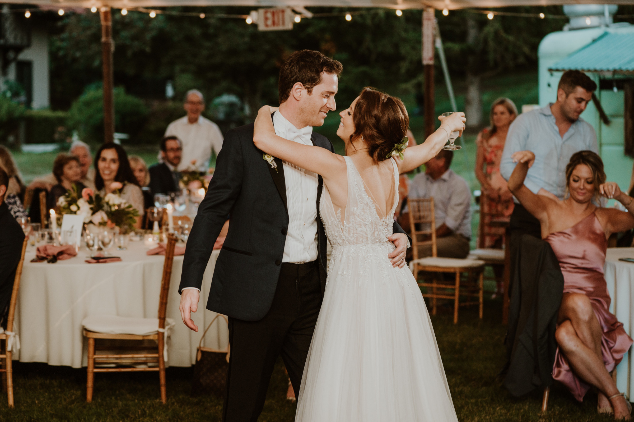 Bride and groom share first dance under glowing string lights at Vermont outdoor wedding.