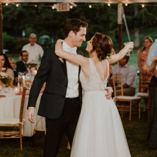 Bride and groom share first dance under glowing string lights at Vermont outdoor wedding.