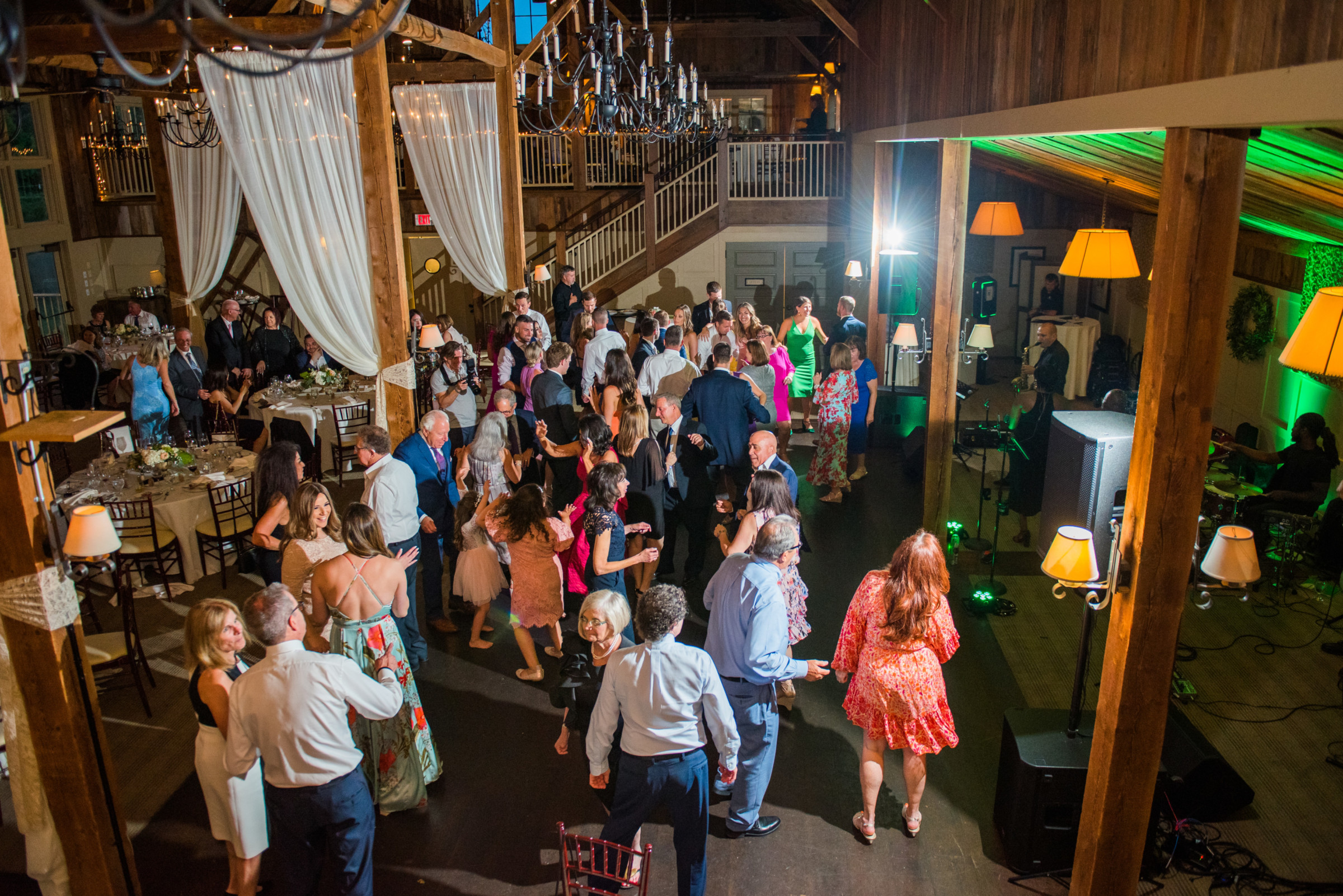 Guests dancing and celebrating at a rustic barn wedding reception with live music and warm lighting.