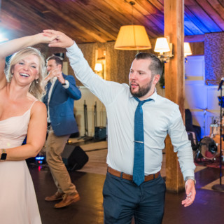 Couple dancing joyfully at rustic wedding reception in The Barn at Gibbet Hill, Groton MA.
