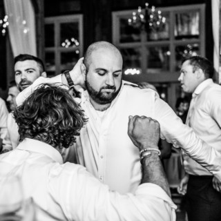 Men dancing joyfully at a black-and-white wedding celebration in The Barn at Gibbet Hill.
