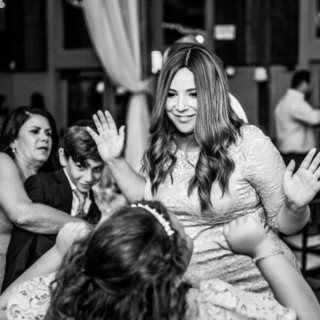 Woman and young girl dancing joyfully at a rustic black and white barn wedding.