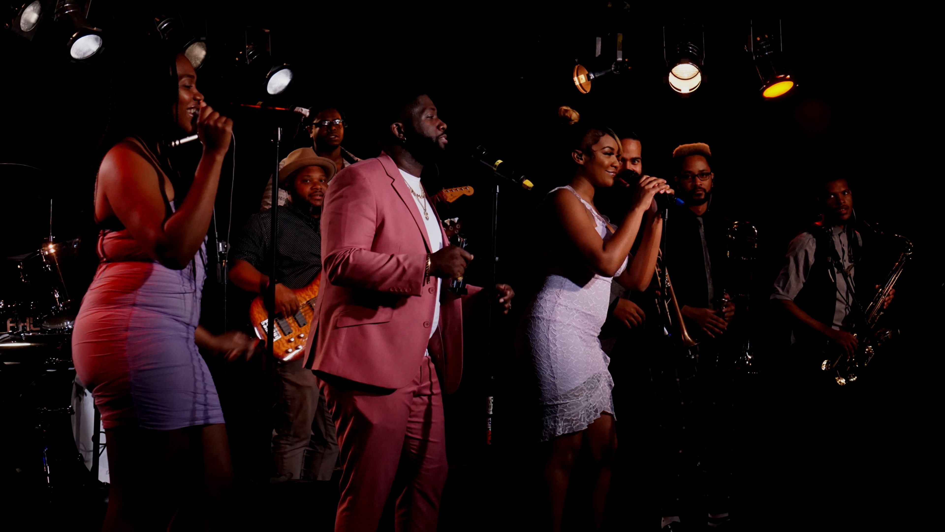 The Philadelphia International Ensemble performing soulful R&B live under warm golden stage lights.